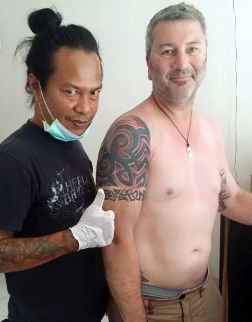 Artist and client showing a fresh tribal shoulder tattoo